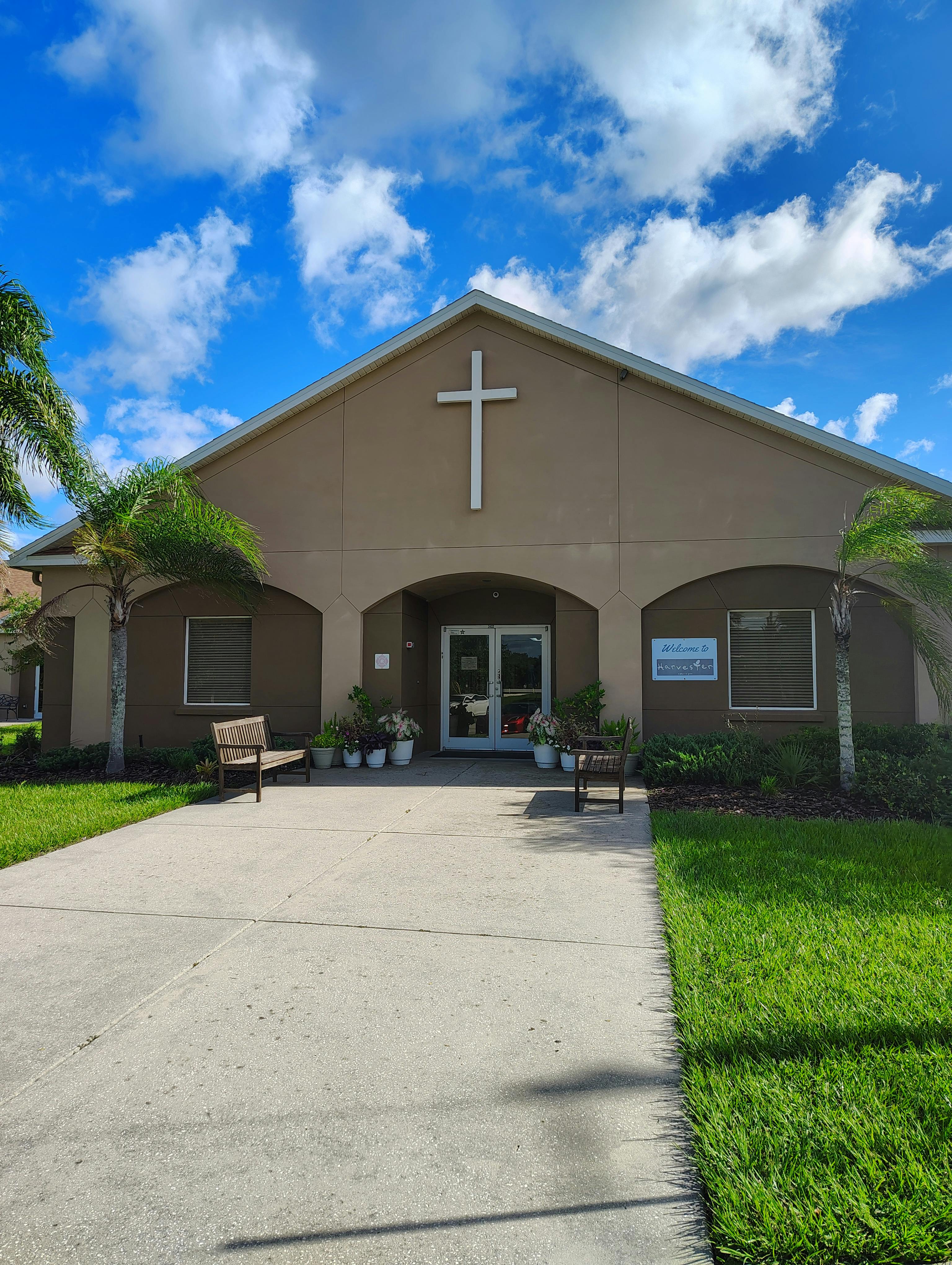 Building with a cross on the facade and a concrete path leading to the entrance