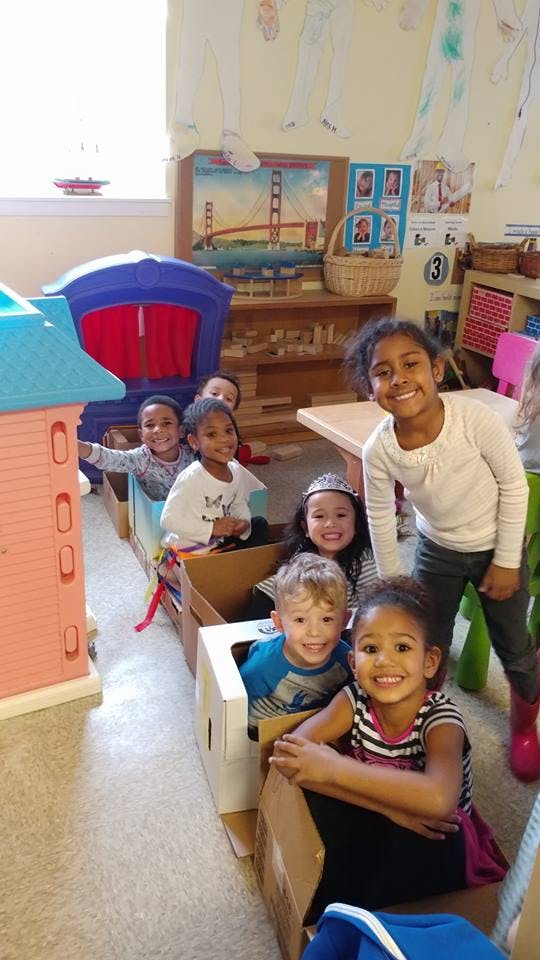 Children playing in cardboard boxes in a classroom