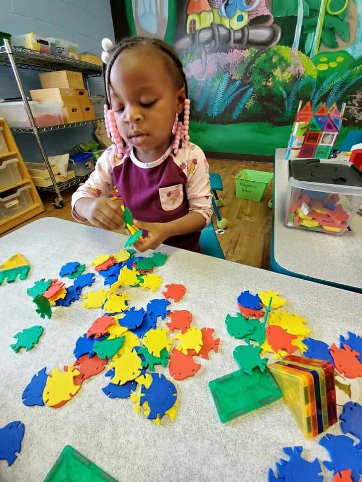 Child playing with colorful fish-shaped foam pieces on a table