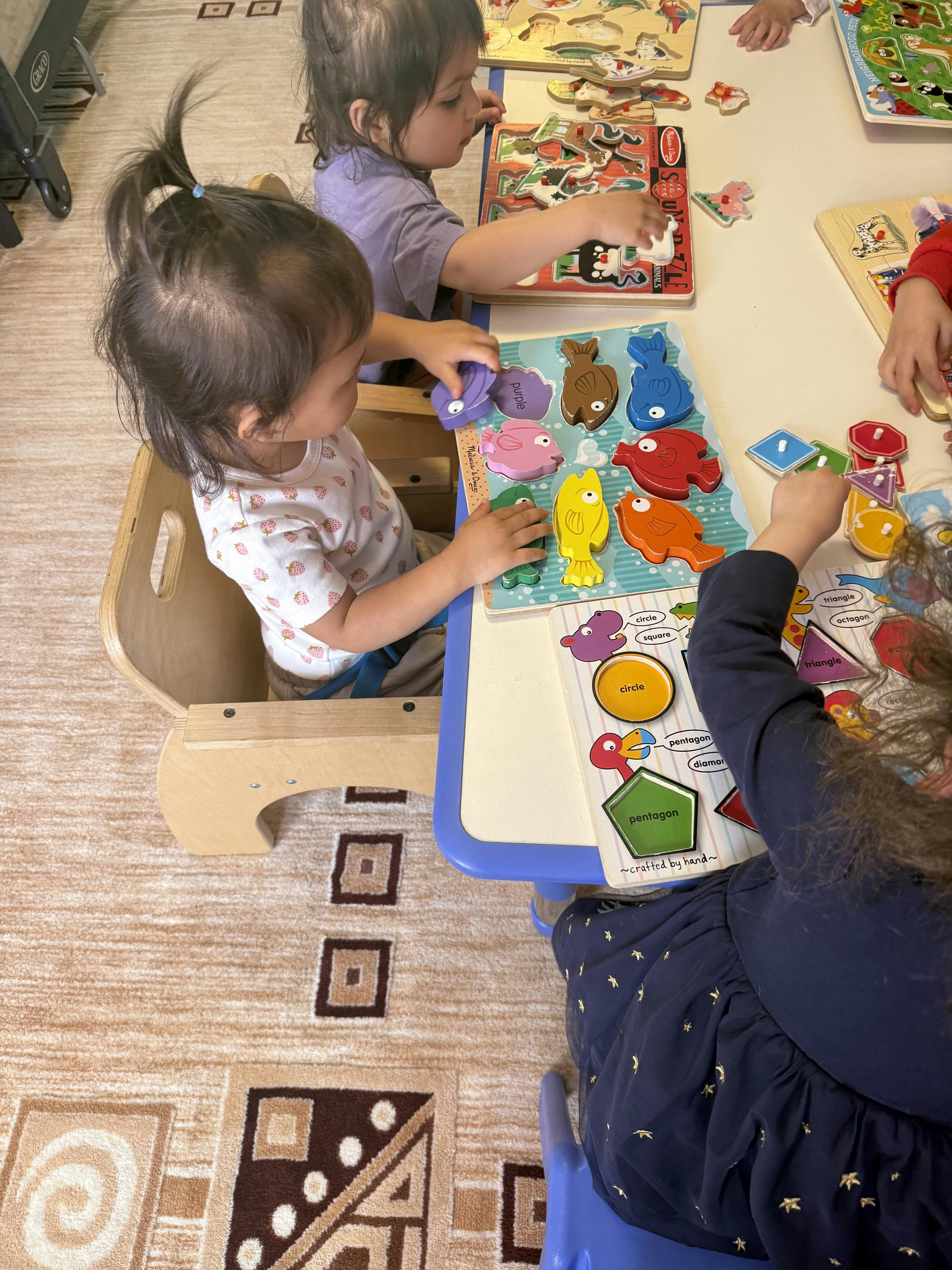 Children playing with colorful shape and animal puzzles at a table