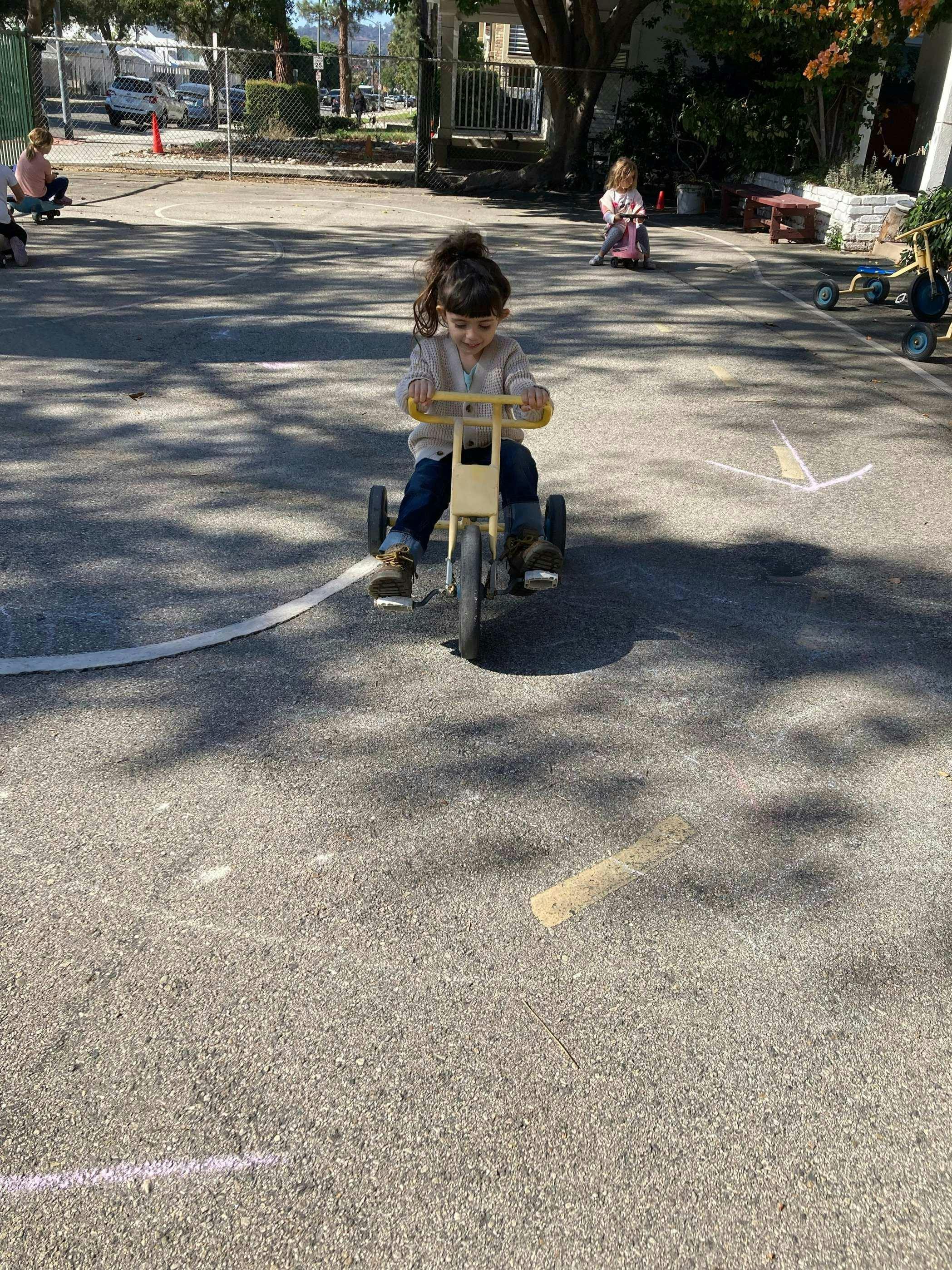 Child riding a tricycle on pavement