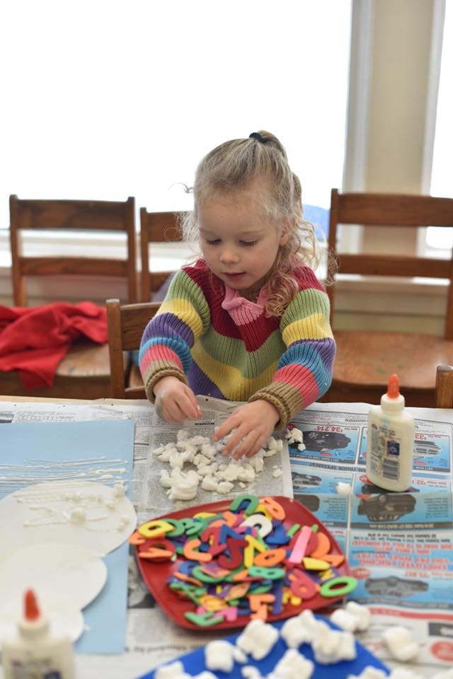 Child making a craft with cotton balls and glue