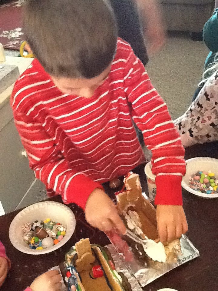 Child decorating a gingerbread house with frosting