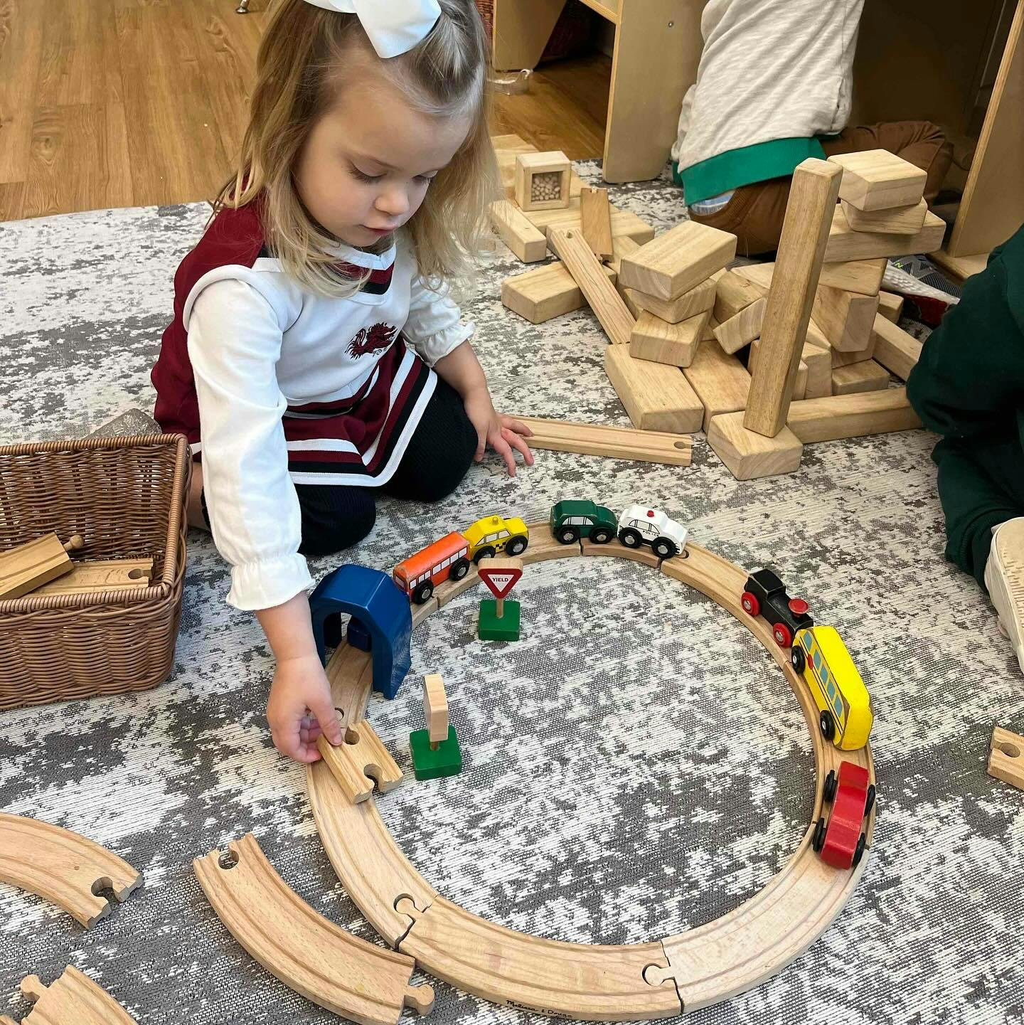 Child playing with a wooden train set on the floor