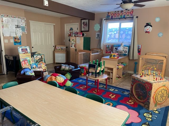 Daycare room with tables, chairs, cribs, and toys