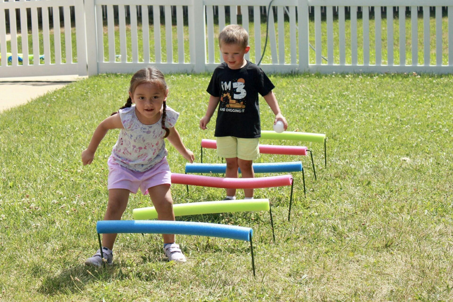 Two children playing with colorful hurdles on grass