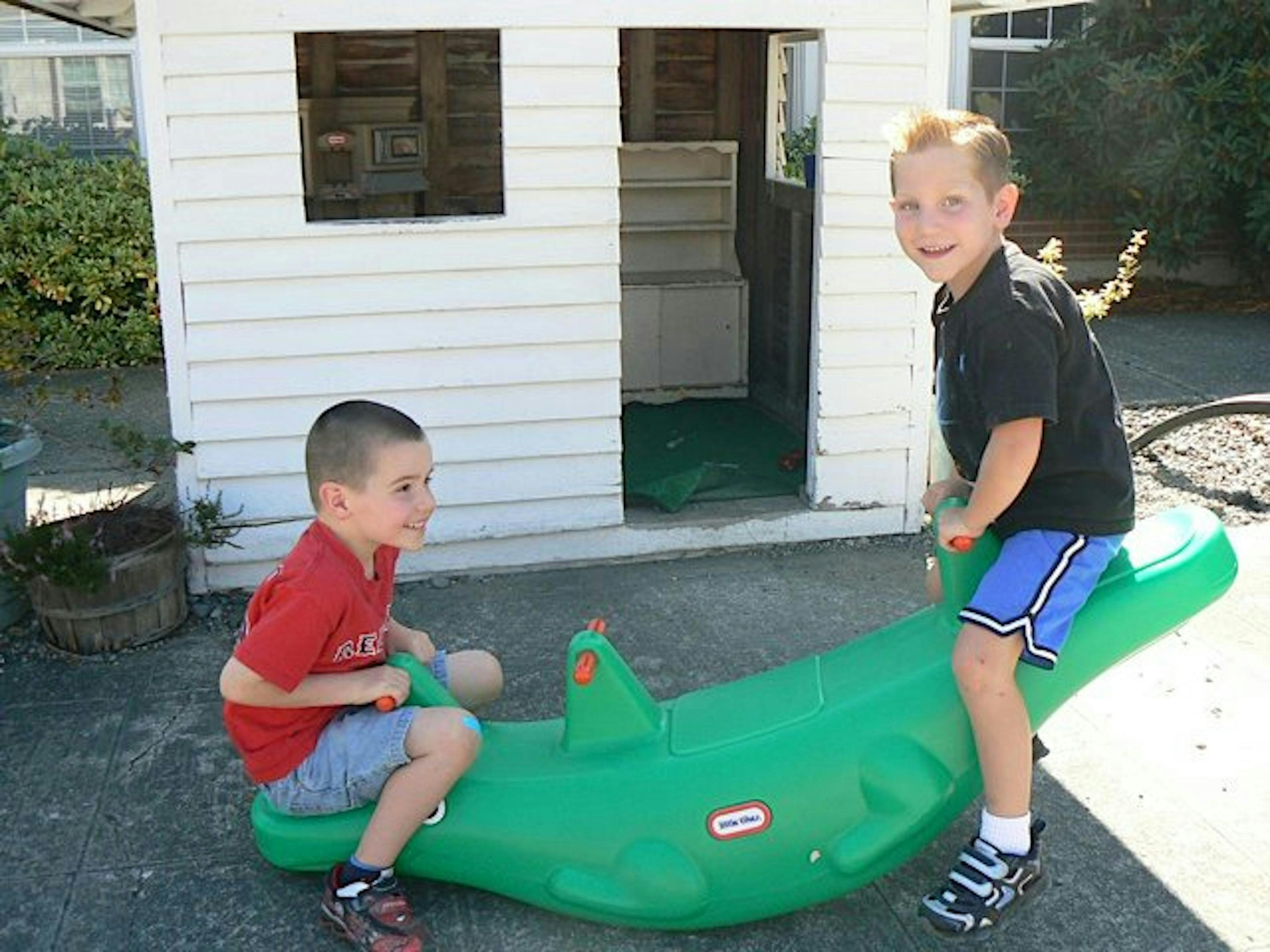 Two children on a green seesaw toy