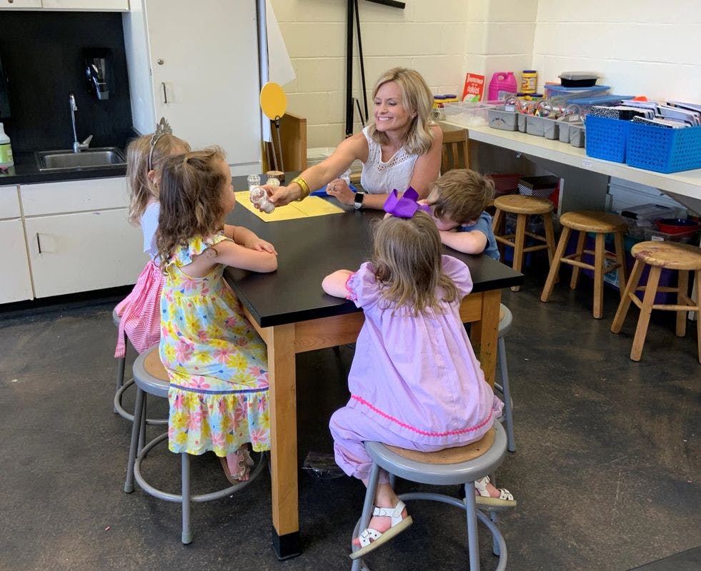 Adult person interacting with children seated around a table