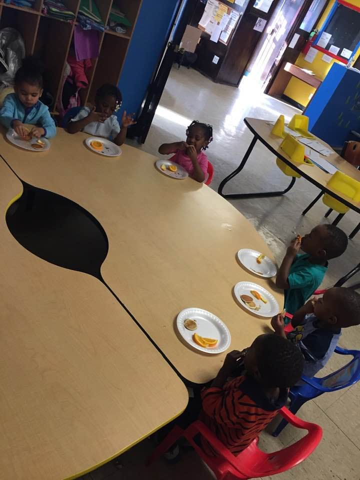 Children eating snacks at a table in a classroom