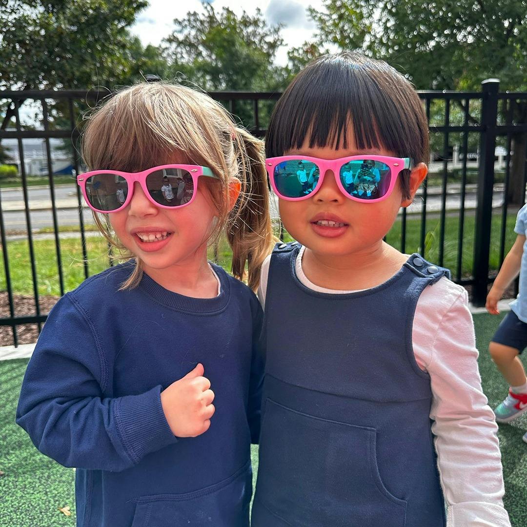 Two children wearing pink sunglasses