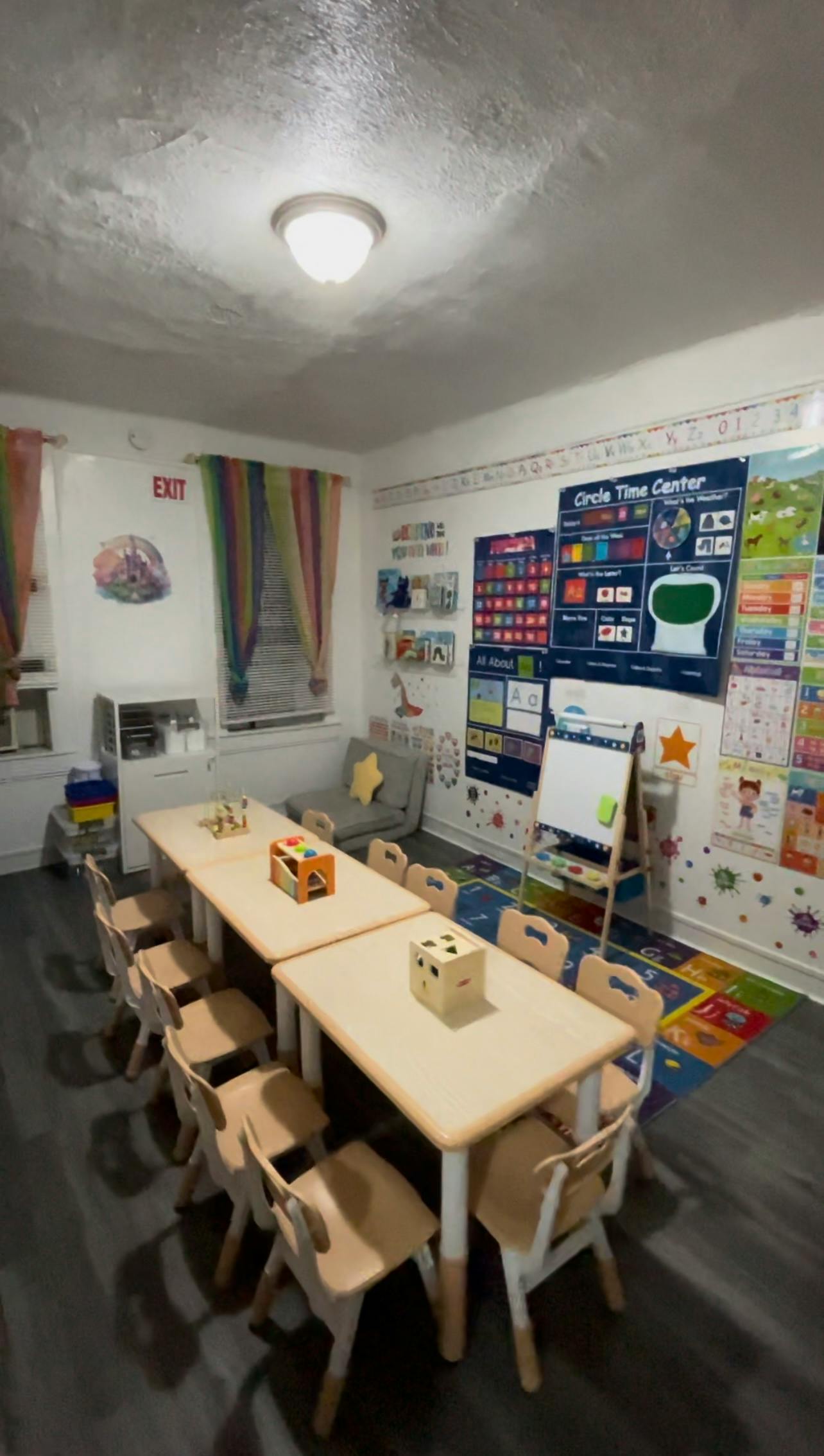 Classroom with small tables and chairs, educational posters on the wall