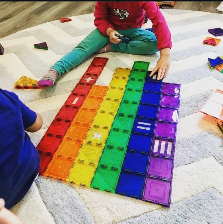 Child playing with colorful magnetic tiles on a rug