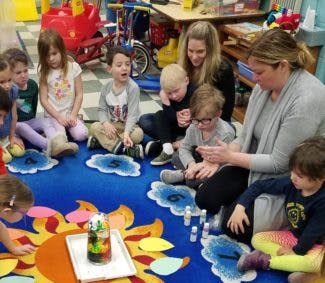 Adults and children sitting on a rug in a classroom