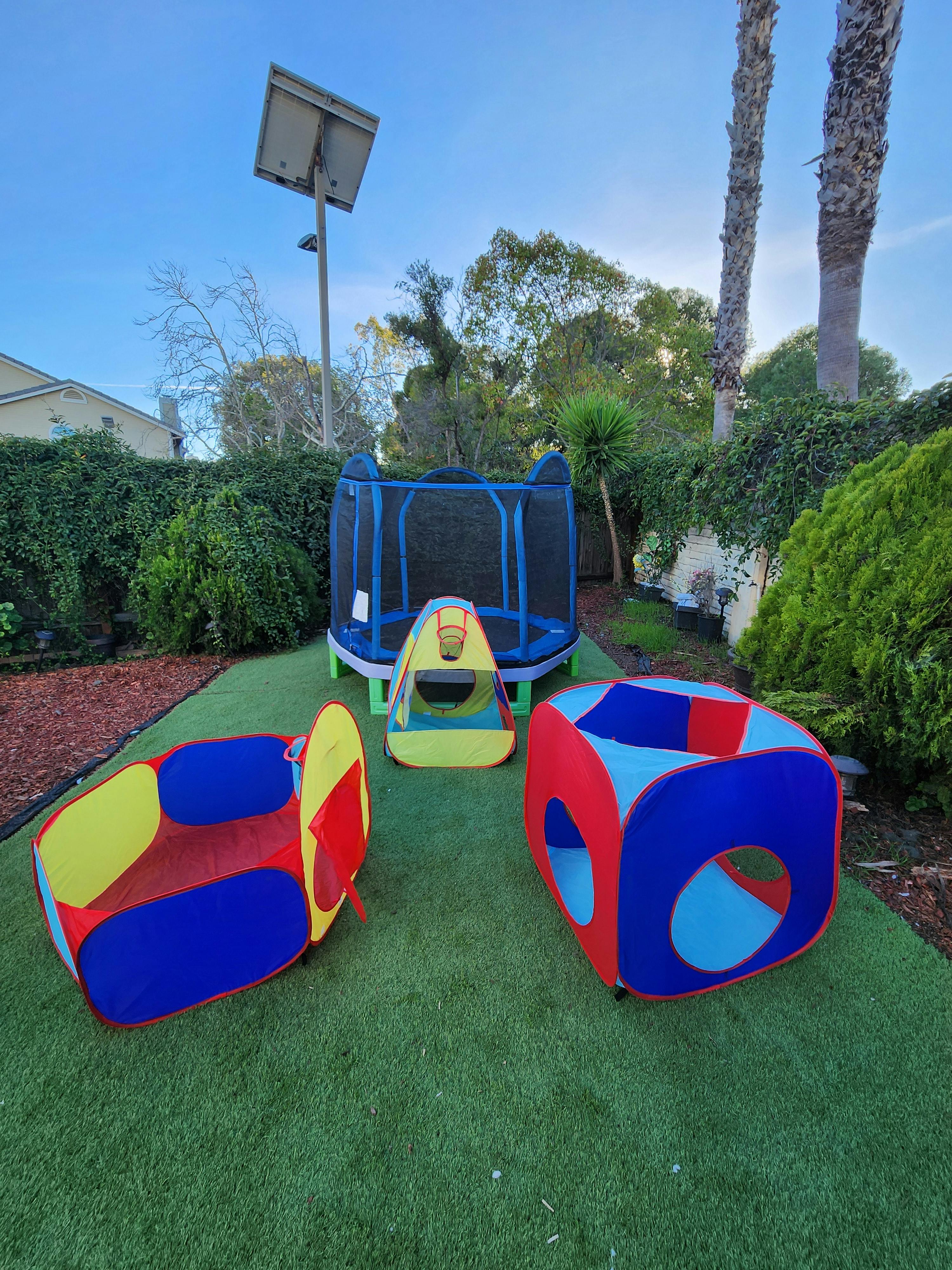 Trampoline and colorful play tents on artificial grass