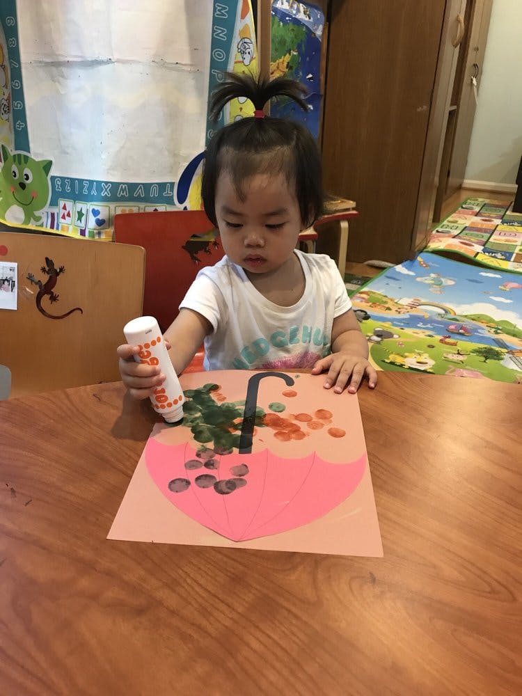 Child making art with an umbrella cutout and paint daubers