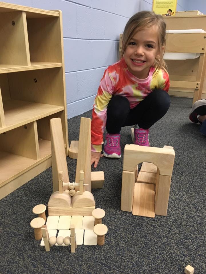 Child crouching on floor with wooden blocks