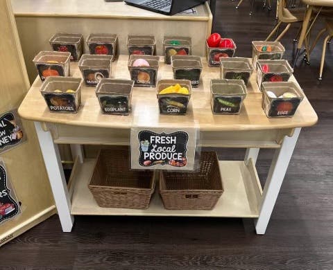 Table with small containers of produce and a "Fresh Local Produce" sign