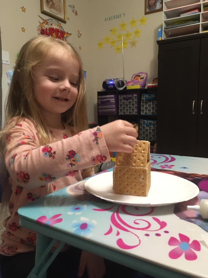 Child building a structure with graham crackers on a white plate