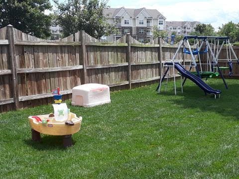 Backyard with a wooden fence, swing set, slide, and water table