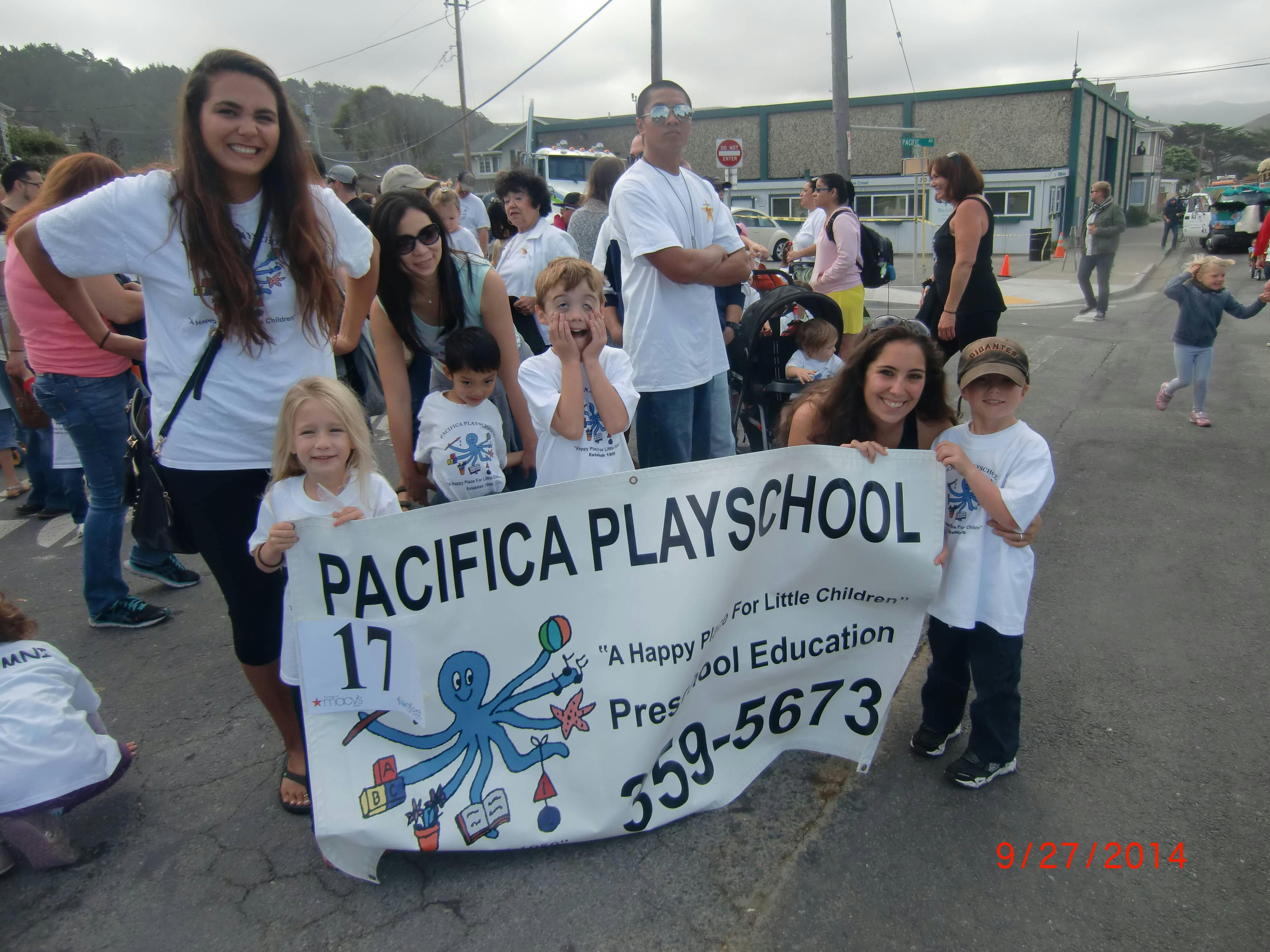 People and children holding a banner that reads "Pacifica Playschool"