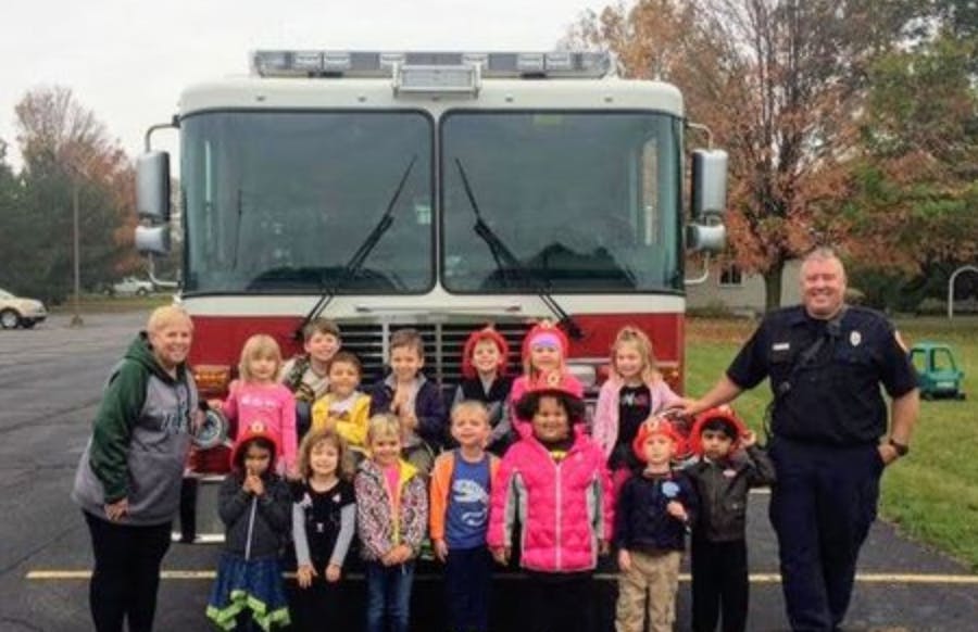 Adults and children posing in front of a fire truck