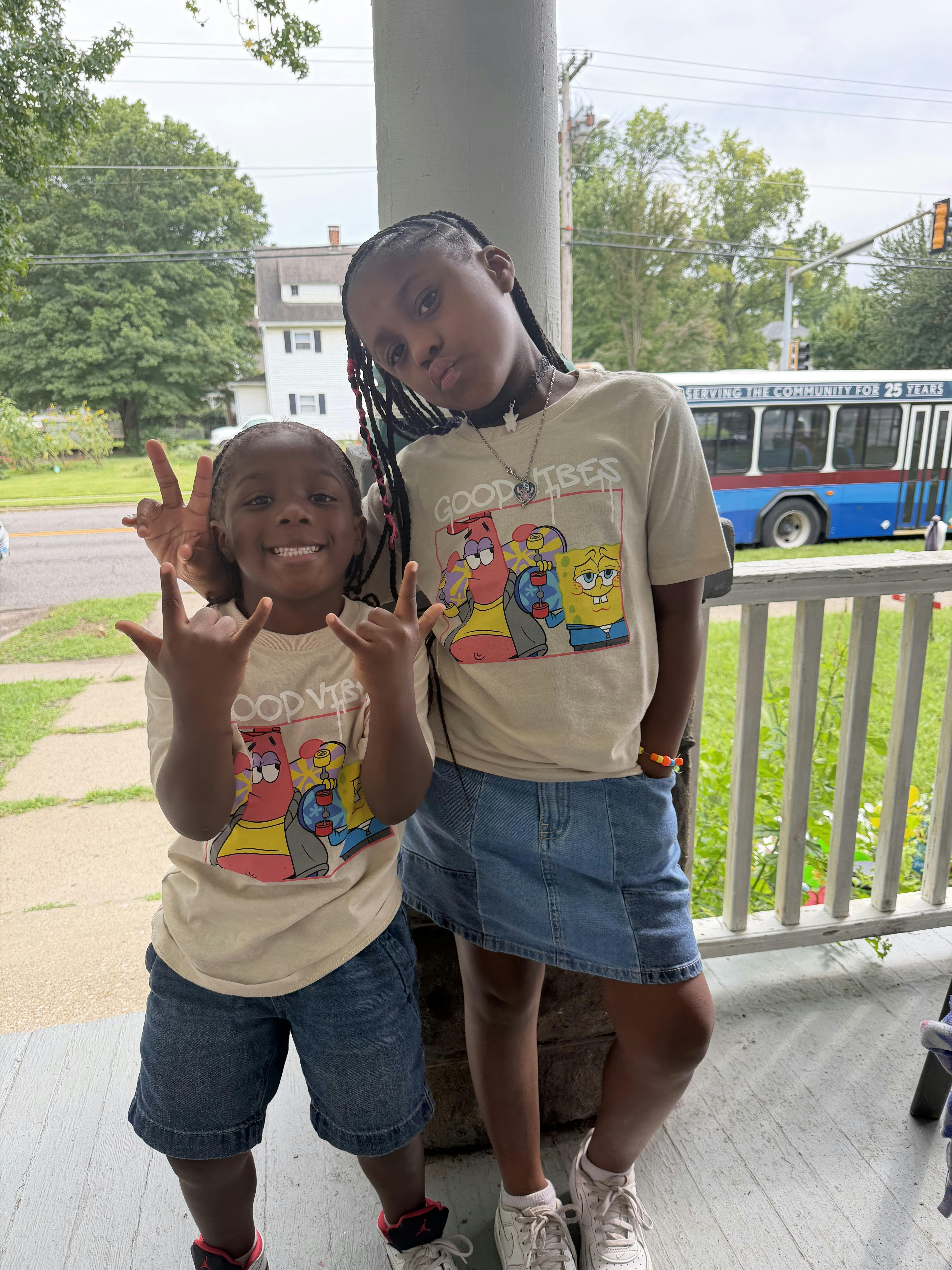 Two children standing on a porch posing for a photo