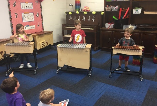 Children playing musical instruments in a classroom