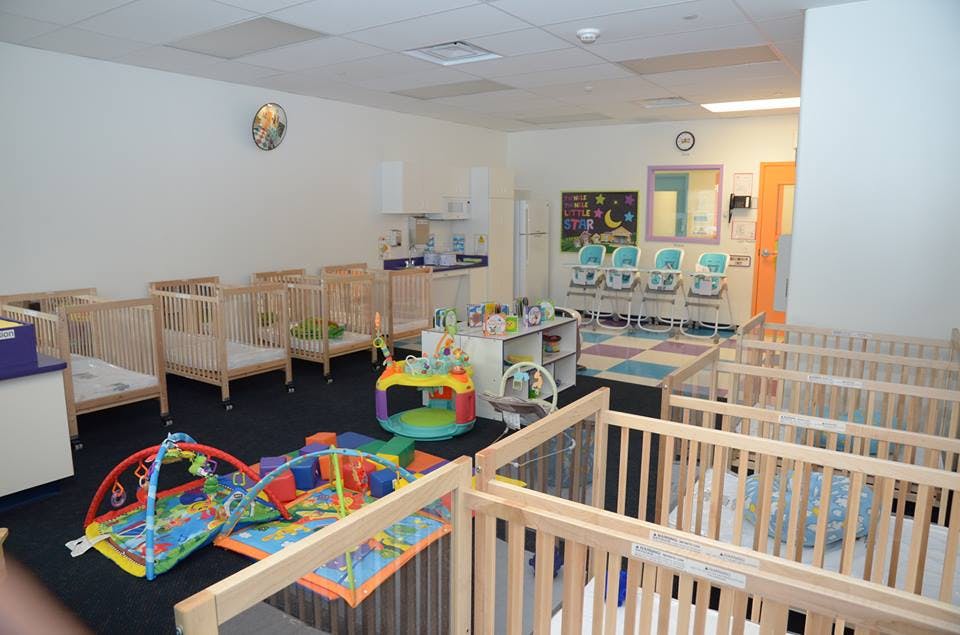 Room with multiple cribs, play mats, and high chairs