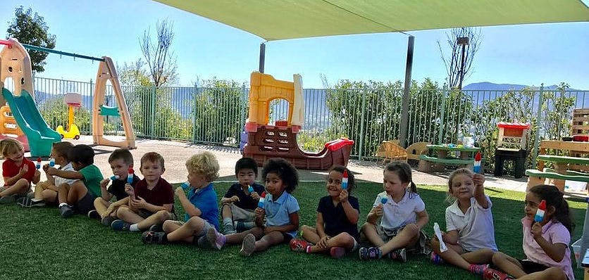 Group of children sitting on grass in a playground