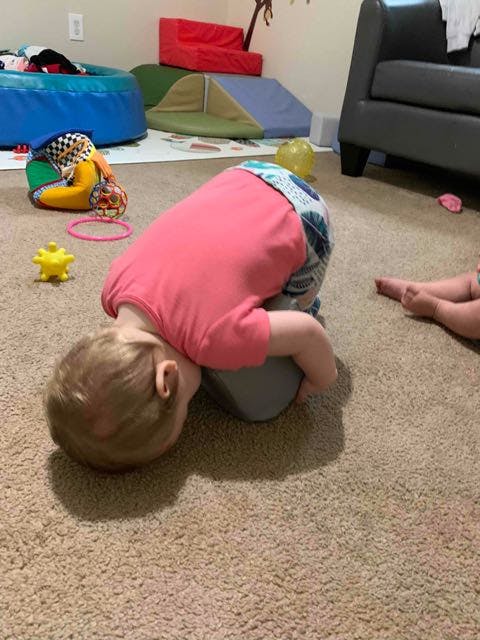 Child on hands and knees with head down on the floor