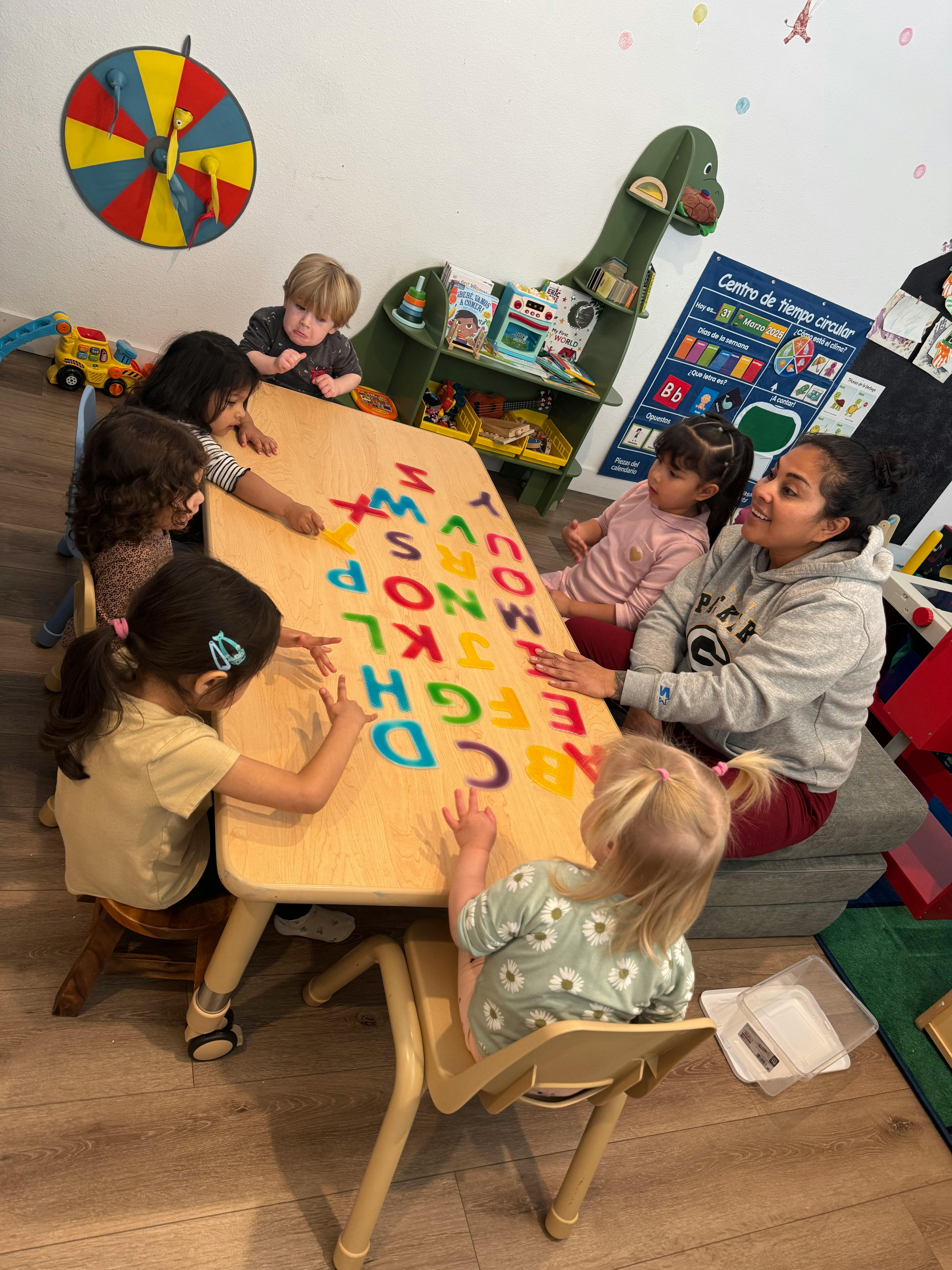 Adult and children around a table with colorful alphabet letters