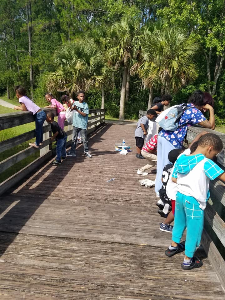 Group of children and adults looking over a wooden railing on a bridge
