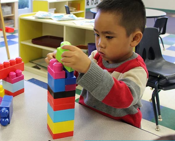 Child stacking colorful building blocks in a classroom
