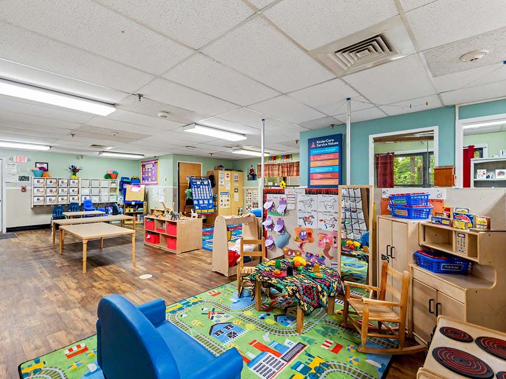 Colorful kindergarten classroom with child-sized tables, chairs, and play areas
