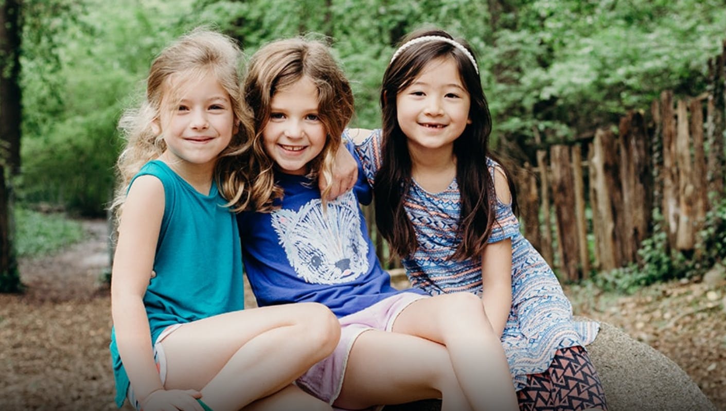 Three children sitting together outdoors