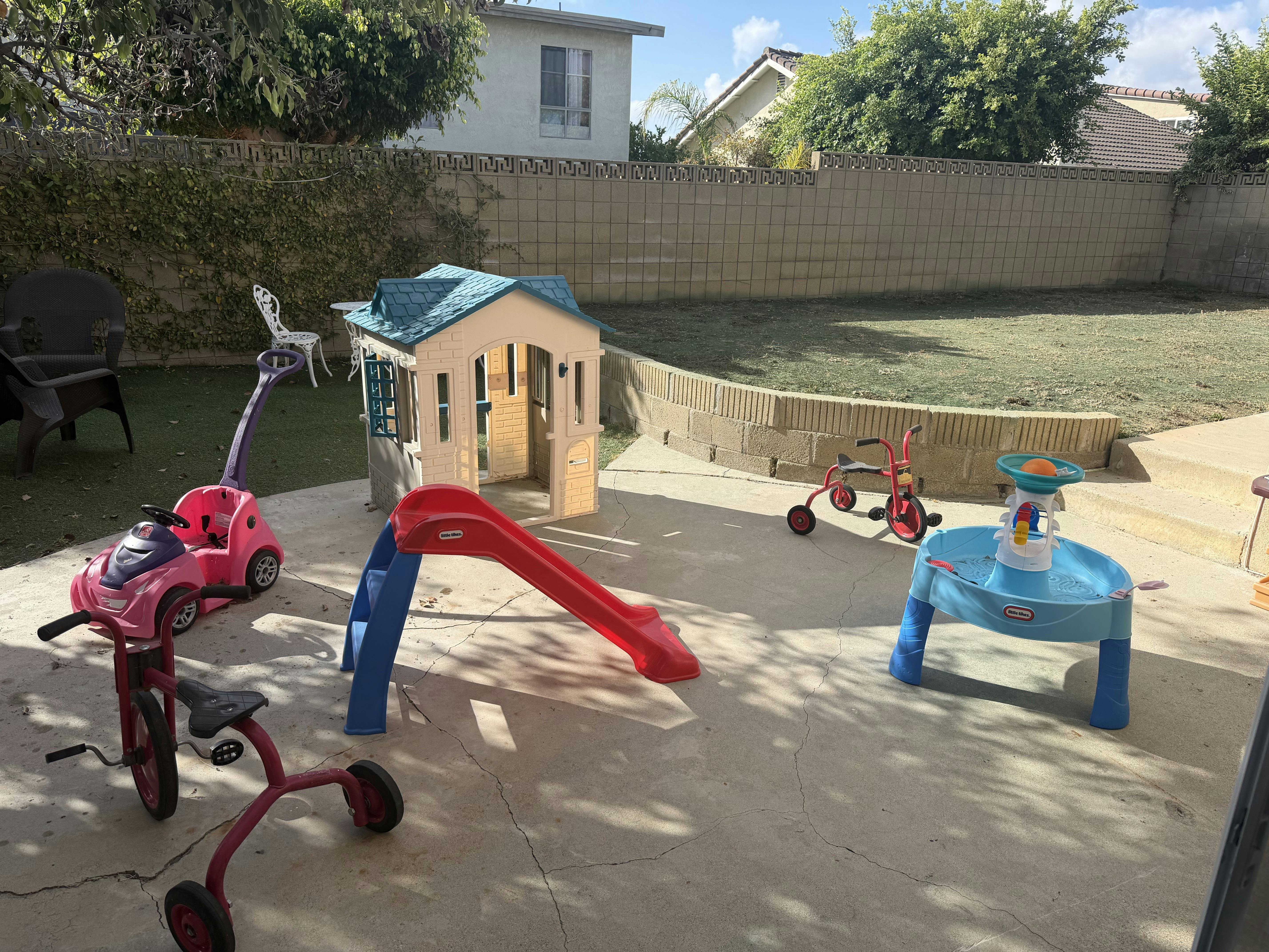 Playground equipment including a playhouse, slide, and water table on a patio