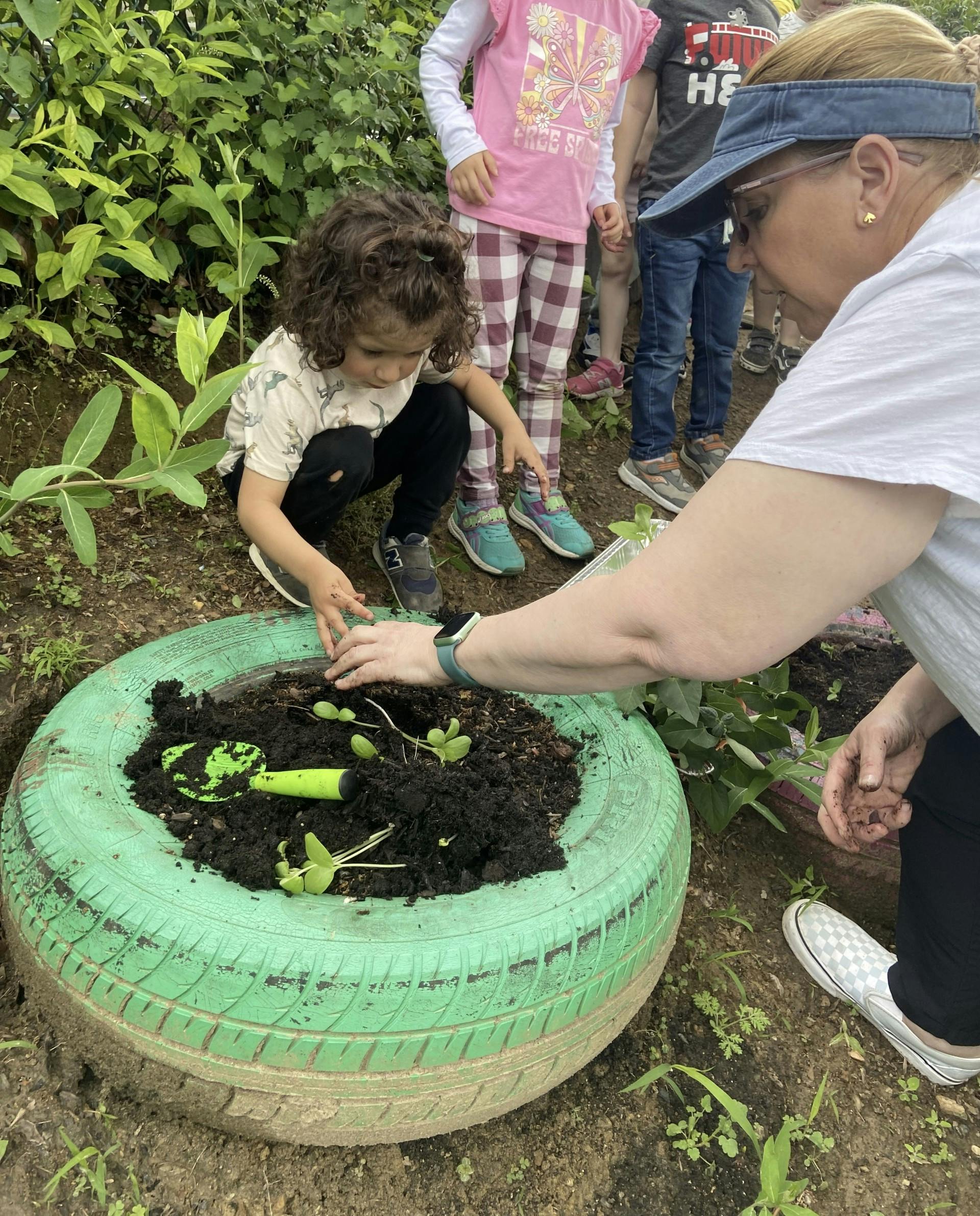 Adult and child gardening in a green tire planter
