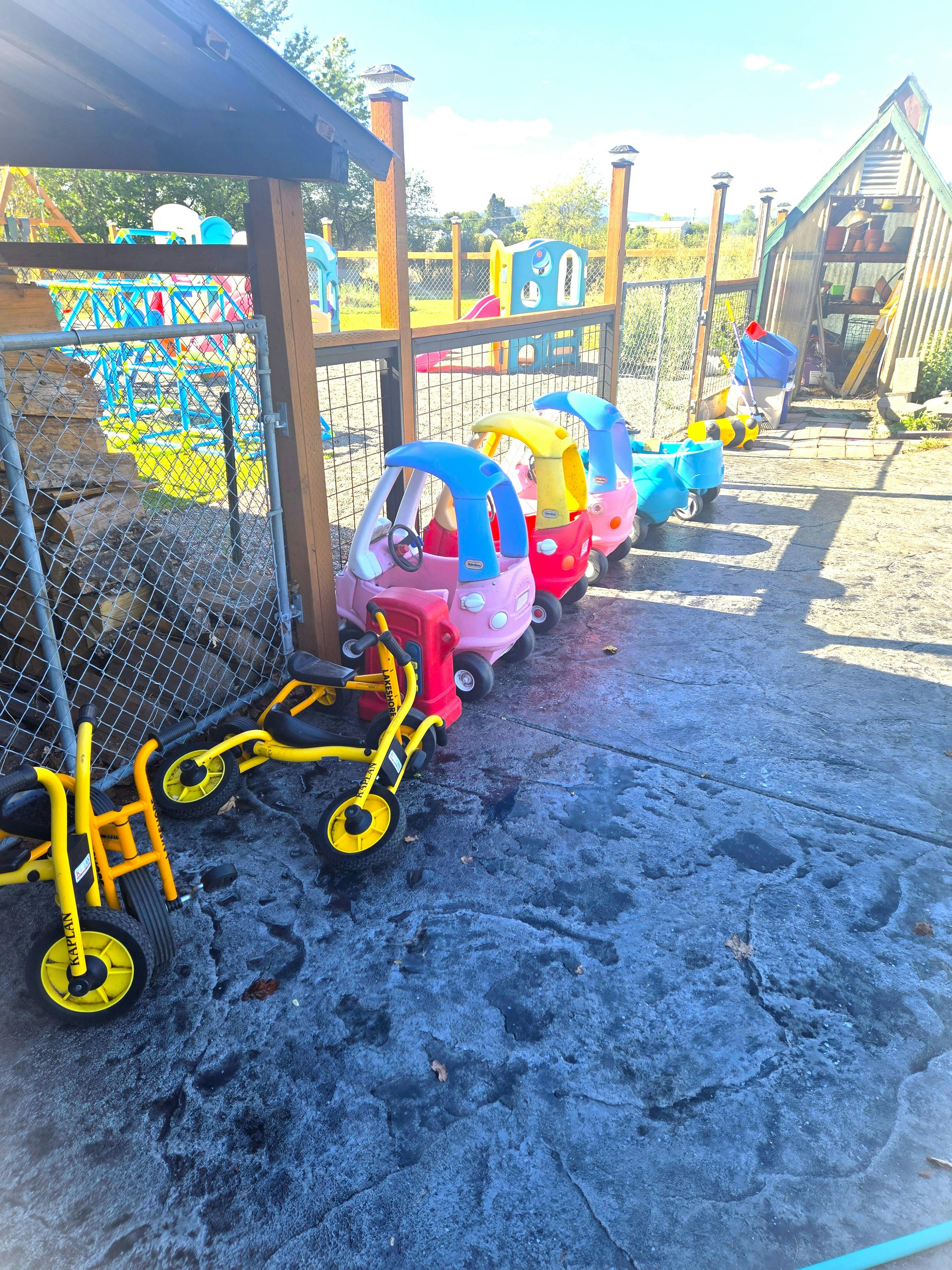 Toy cars and tricycles parked on a playground patio