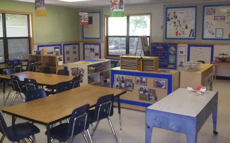 Empty classroom with tables, chairs, and learning materials