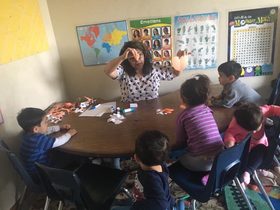 Person and children gathered around a table in a classroom