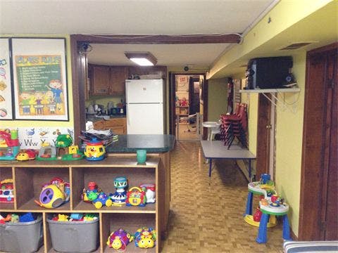 Playroom with shelves of toys and a view into a kitchen and hallway