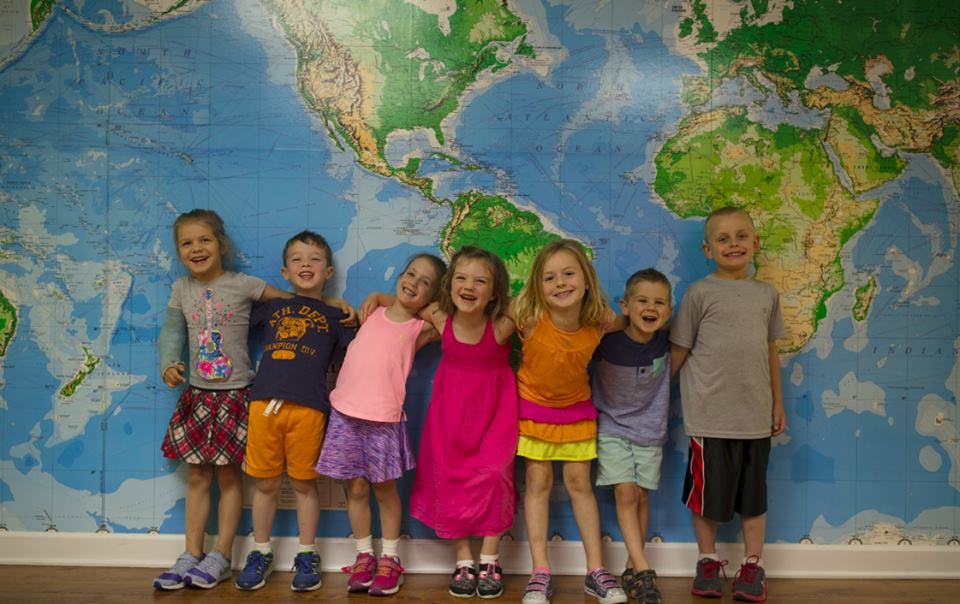 Seven children standing in front of a world map