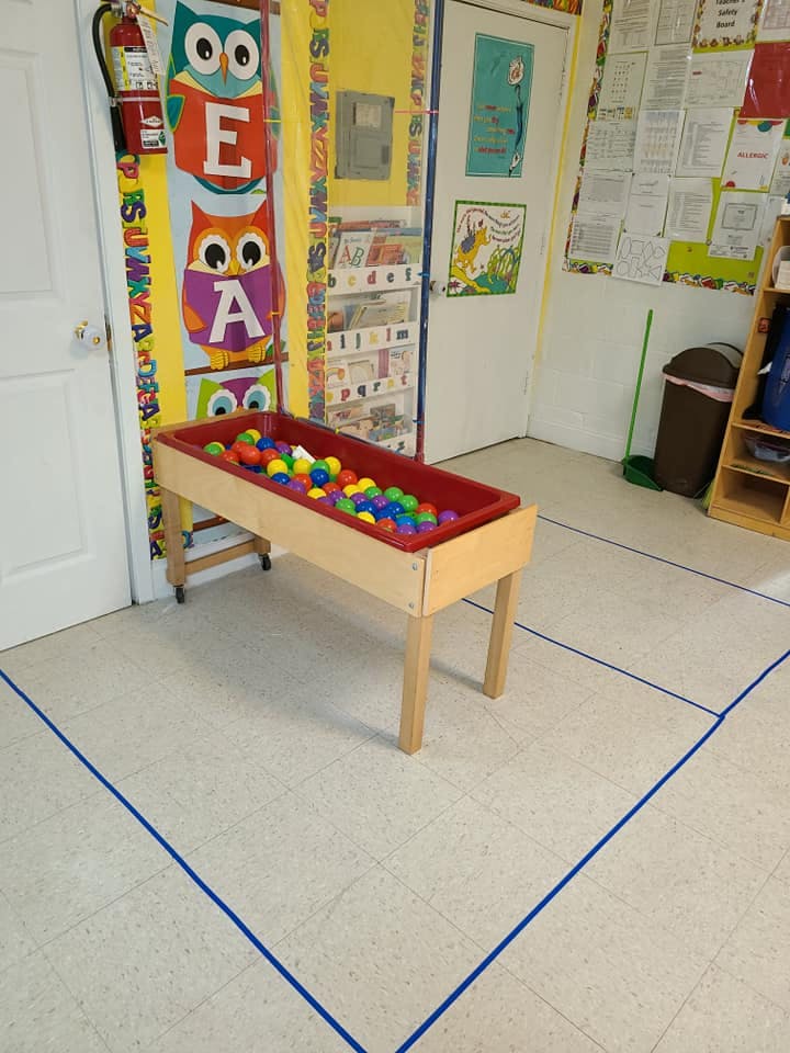 Playroom with a red bin full of colorful balls on a wooden stand