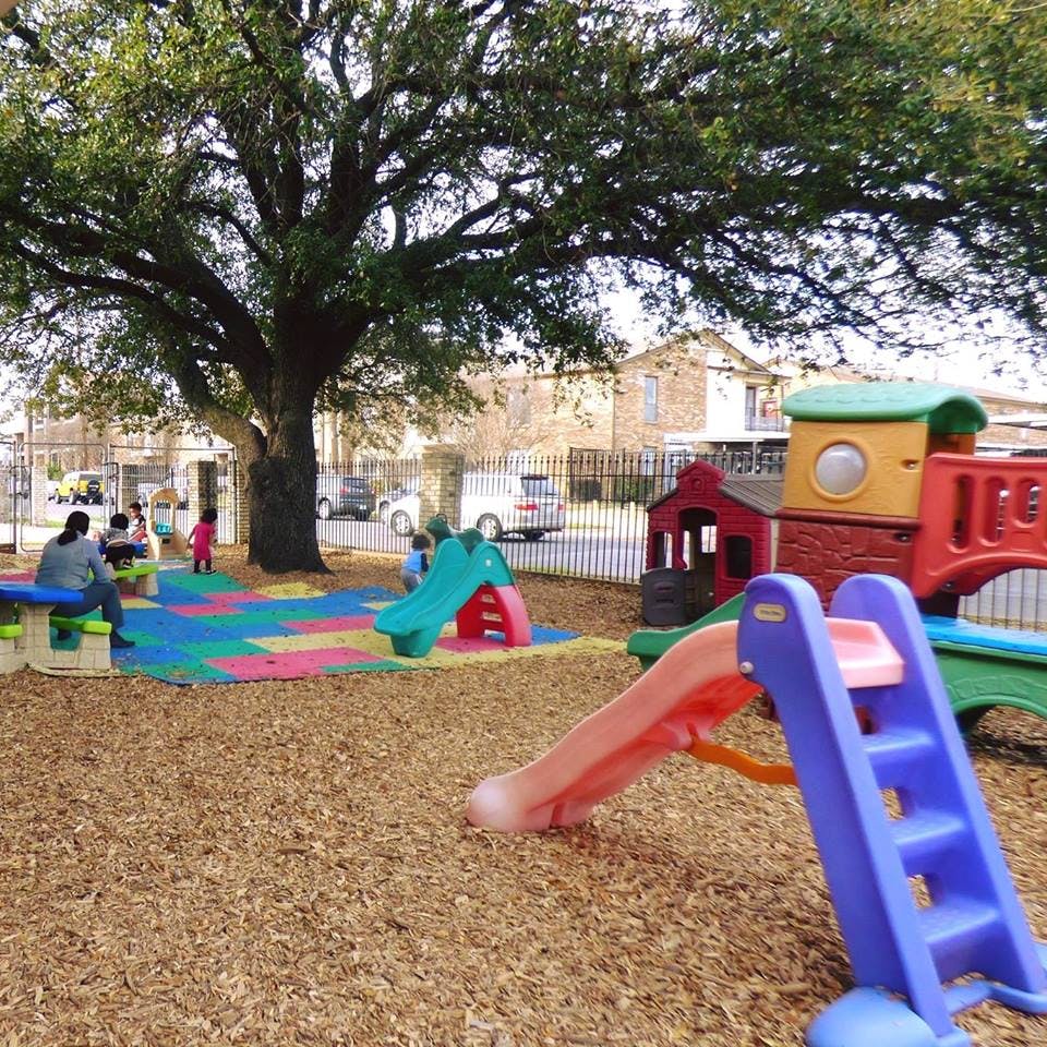 People and children on a playground with slides and colorful mats