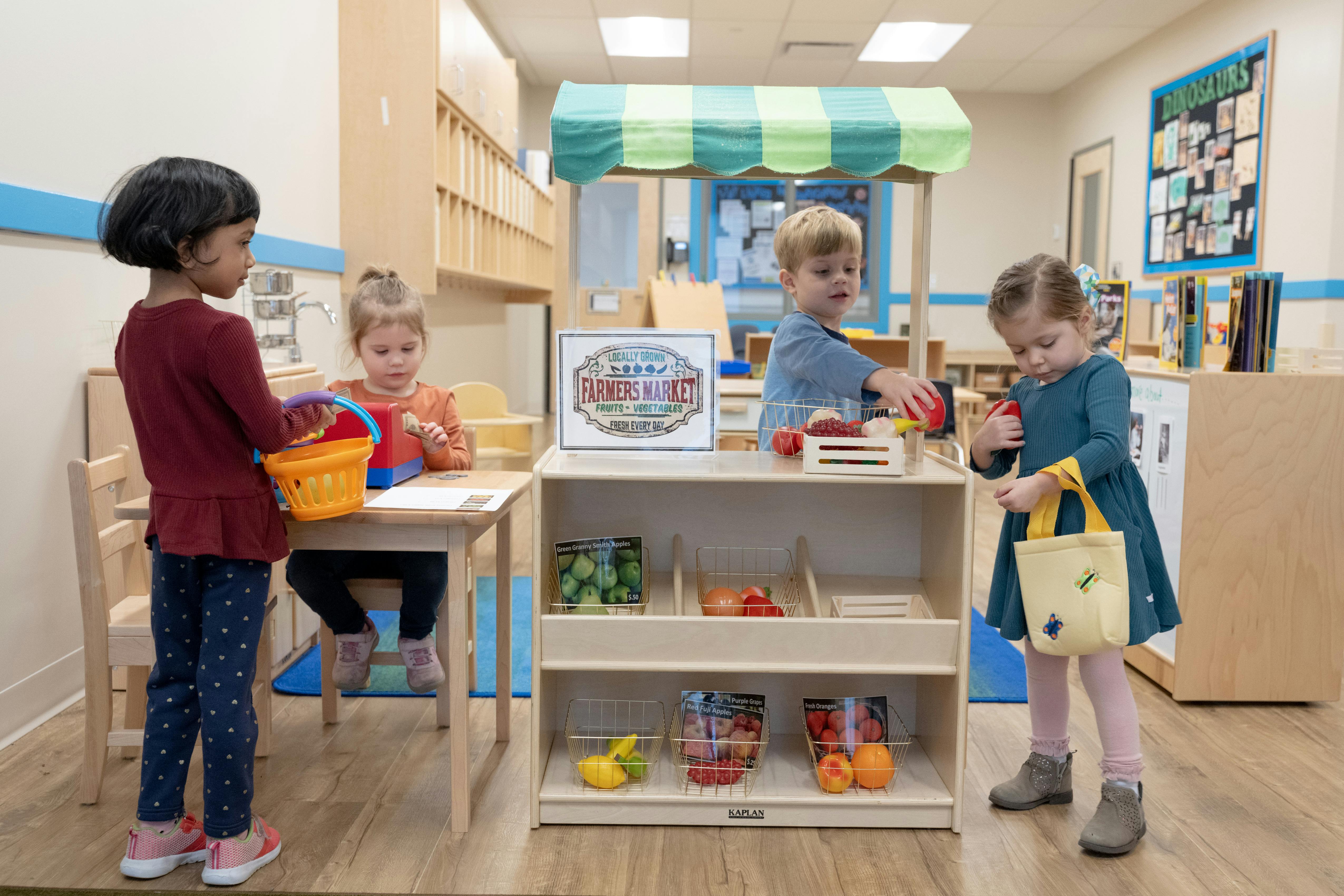 Children playing in a classroom with a toy market stand