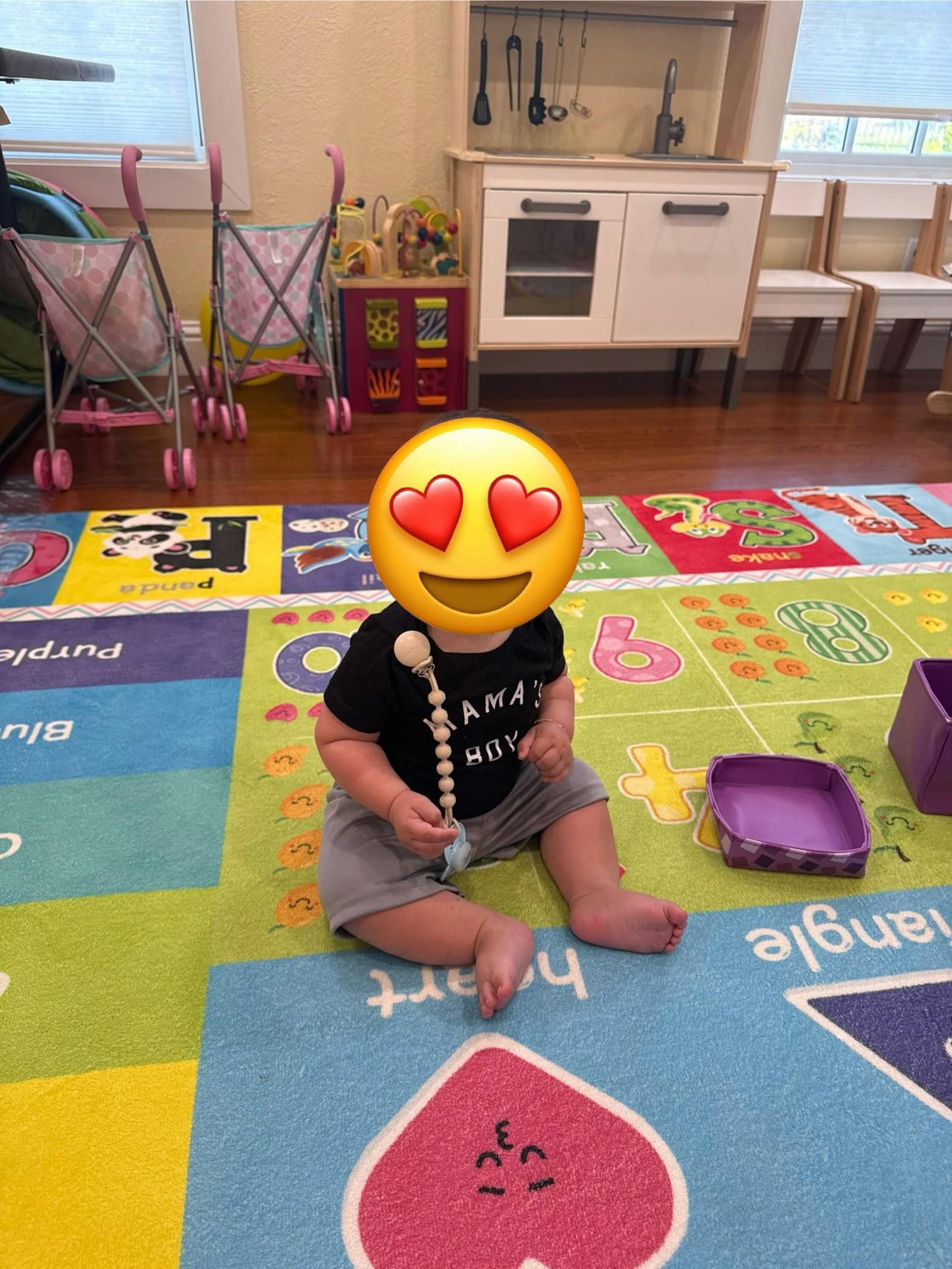 Child sitting on a colorful playmat holding a toy