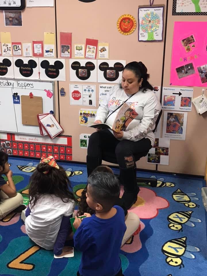 Person reading a book to children in a classroom