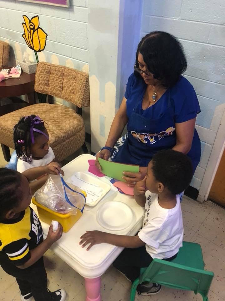 Adult and three children at a table with craft supplies