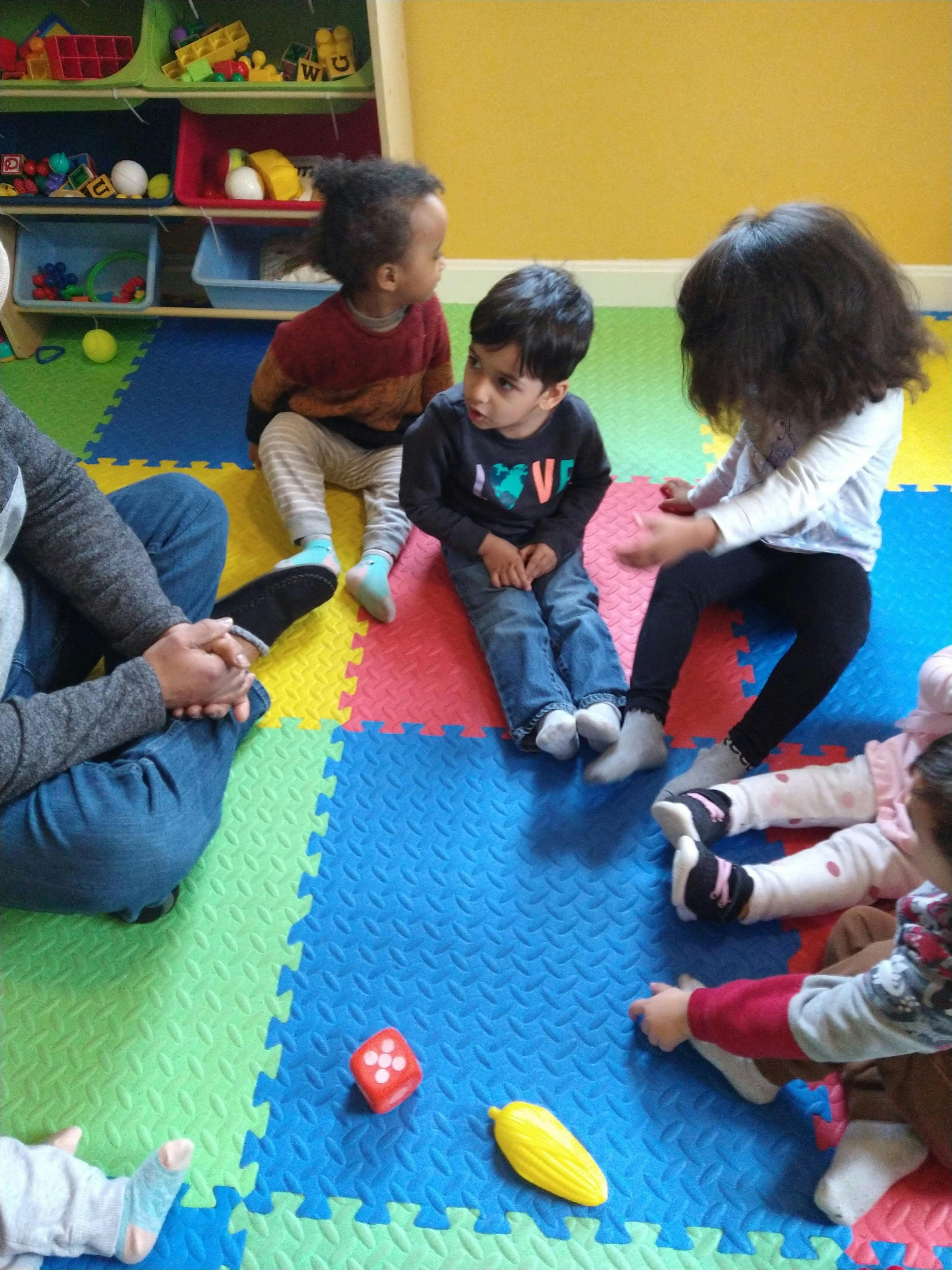 Children sitting on a colorful mat with an adult in a classroom