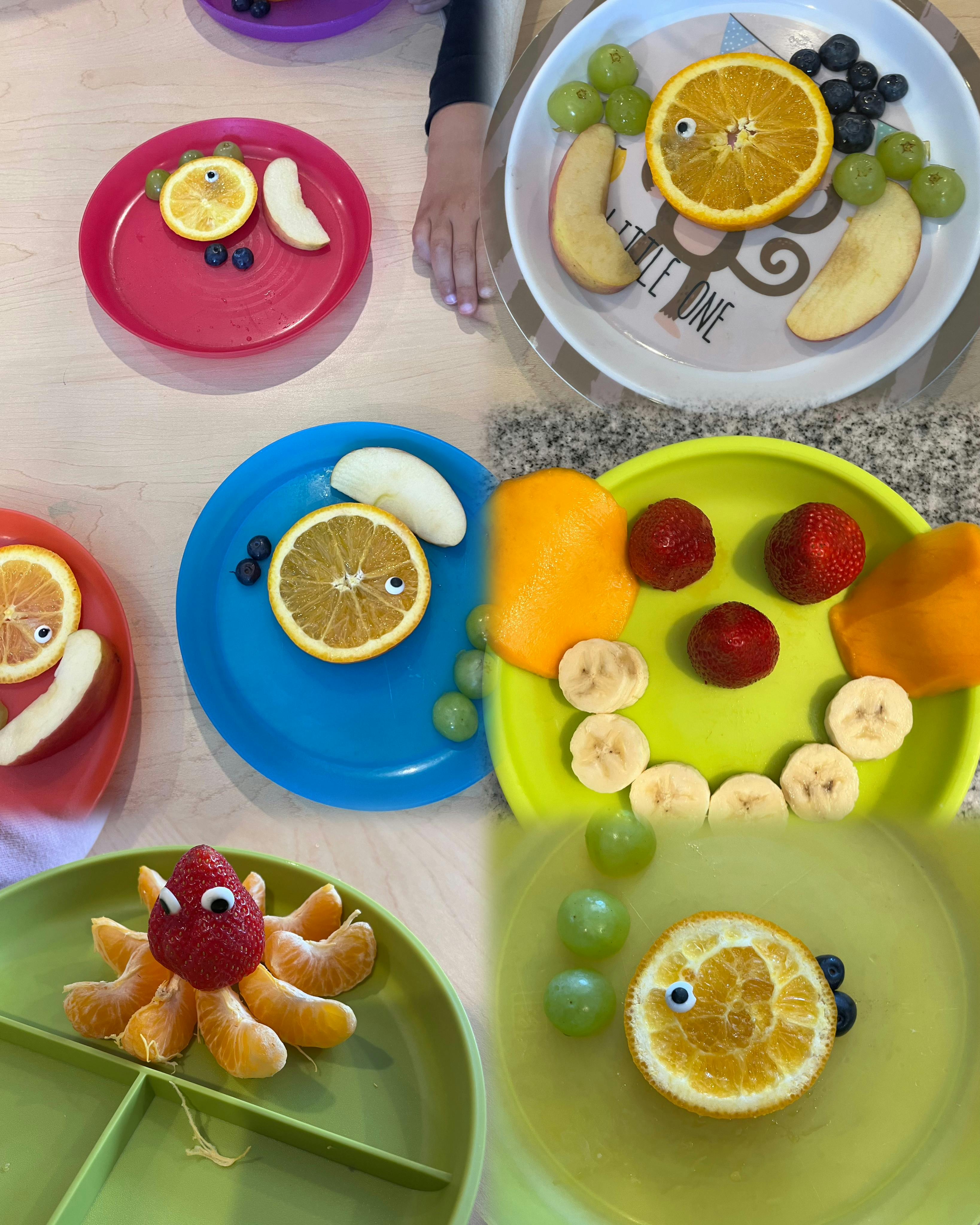 Multiple plates with fruit arranged to look like faces and animals
